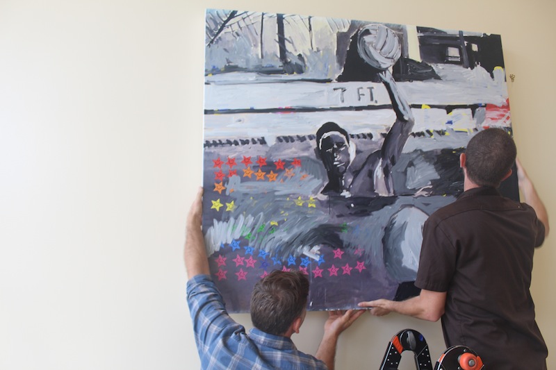 Students hang one of Franco's paintings, inspired by his 1993 yearbook, at the Media and Arts Center. Photo by Adele Bloch